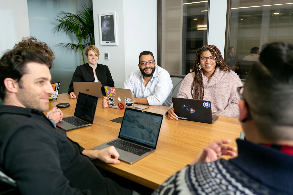 A team meeting around a table with laptops